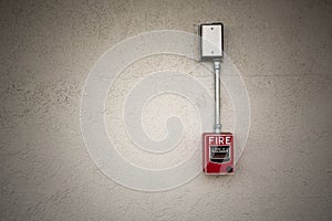 Red fire alarm switch at white wall