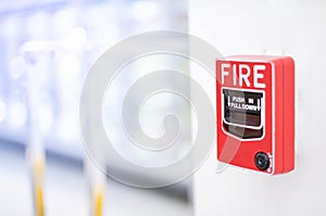 The red fire alarm switch on the white wall at the supermarket