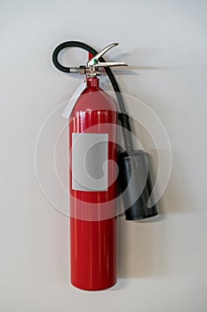 Red fire extinguisher hanging against white background