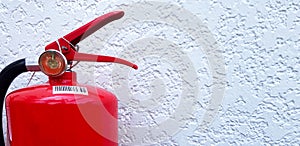 Red fire extinguisher on white rough concrete wall with copy space on right.