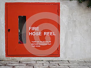 Red fire hose reel on concrete wall