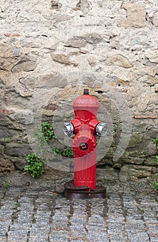 Red fire hydrant against a stone wall