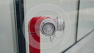 Red fire hydrant pipe stands on street near windows of office building closeup