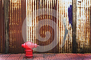 Red fire hydrant with rusty corrugated iron metal fence zinc wall background with copy space