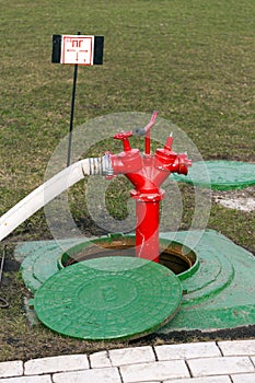 Red fire hydrant stands in manhole