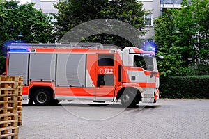 Red fire truck in the courtyard of a multi-storey building arrives on call, emergency 112 concept for a fire in Germany, flashing