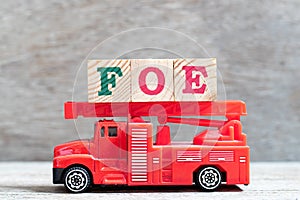 Red fire truck hold block in word foe on wood background