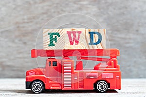 Red fire truck hold block in word FWD Abbreviation of forward on wood background