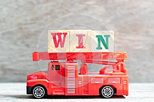 Red fire truck hold letter block in word win on wood background