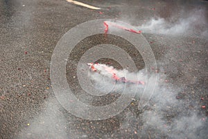 Red firecrackers exploding with smoke on the asphalt