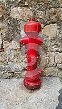 Red fireplug against a stone wall