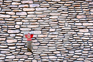 Red fireplug at old style stone wall