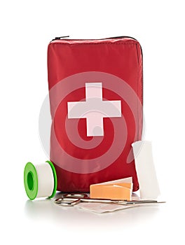 Red first aid medical kit bag with scissors, tape and gloves standing over white