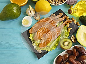 Red fish, avocado, organic nuts lemon on a blue wooden background, healthy food fresh