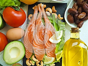 Red fish, avocado, nuts lemon ingredient on a wooden background