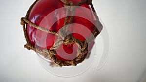 Red fishing glass buoy spins around its axis in a rope