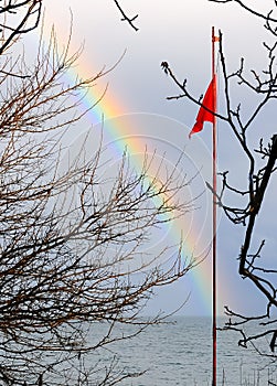 Red flag on the background of a multi-colored rainbow over the sea, the Black Sea