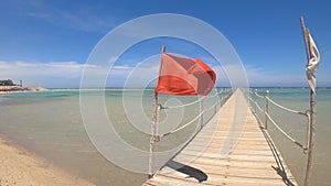 A red flag on the beach warns vacationers of danger in the sea