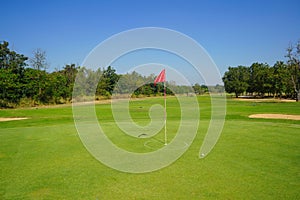 Red flag at the beautiful golf course at the sunrise time. Beautiful golf course in a sunny day. Background evening golf course