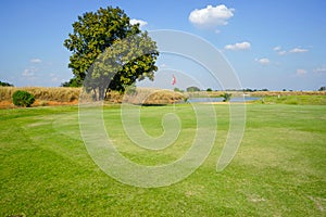 Red flag at the beautiful golf course at the sunrise time. Beautiful golf course in a sunny day. Background evening golf course