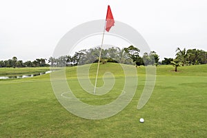 Red flag with Golfball on grass in golf course