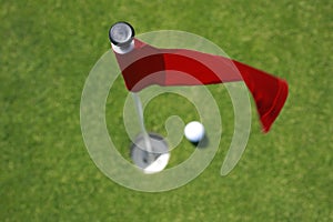 Red flag on green with golf ball.