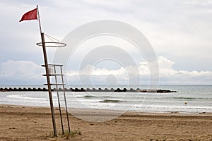 A red flag in a lifeguard tower warn swimmers of danger of bathing in the beach