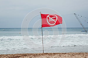 Red flag prohibiting swimming set on the sandy beach