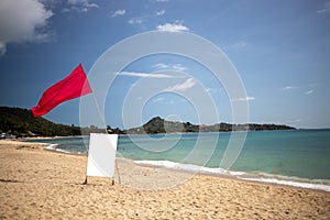 Red flag and a sign with a copy space on an empty tropical beach on a nice day.