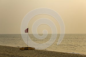 red flag swimming is prohibited and a yellow rescue surf board on a sandy beach against the sea in bad weather