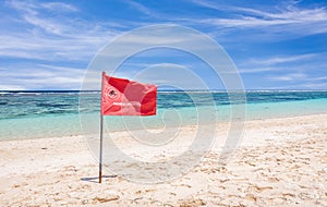 Red flag warning on sandy beach