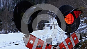 Red Flashing Traffic Light at a Railway Crossing in a Forest in Winter. Train Passing By