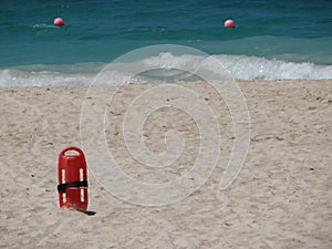 Red fLifesaver lifeguard in sand at beach