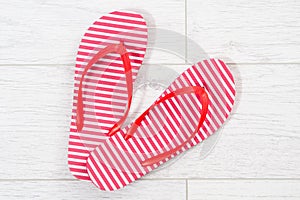 Red flip flops on a white wooden background close up
