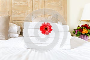 Red flower in fresh white towel pile in the upscale hotel room. Being alone, getaway, staycation, digital detox, trip