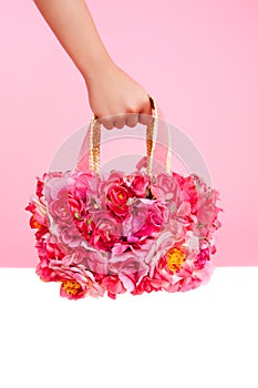 Red flowers bag in woman hand on pink background