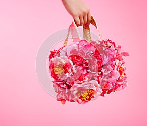 Red flowers bag in woman hand on pink background