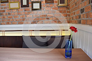 Red Flowers in a glass on the table. Brick wall and frame Background .