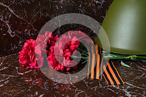 red flowers and an old military helmet on dark marble