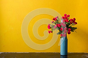 Red flowers in vase on yellow background