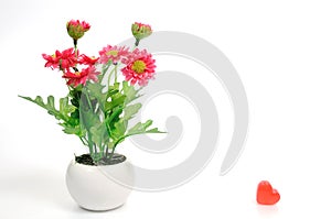 Red flowers in white flower pot with heart, artificially