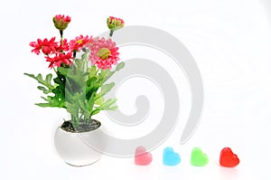 Red flowers in white flower pot with heart, artificially