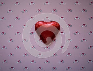 Red foil wrapped heart on pink hearts background