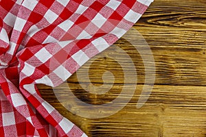 Red folded checkered napkin on rustic wooden kitchen table. Top view, copy space