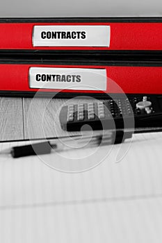 Red folders with contracts written on the label on a desk