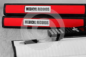 Red folders with medical records written on the label on a desk