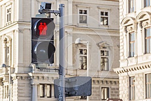 Red forbidding traffic light prohibit for pedestrians to cross the street in european city on background of old classic building.