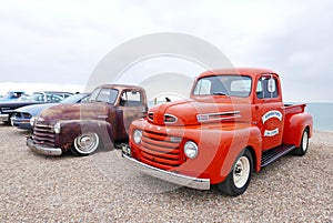 Red 1949 Ford F1 Pickup with other cars parked on a beach