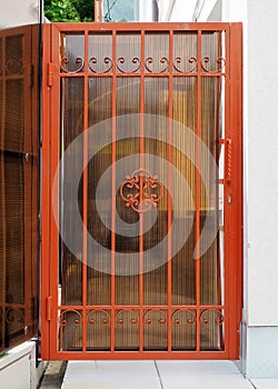 Red forged gate of private house. Forged patterned lattice on the gate of the house. Entrance to a private area.