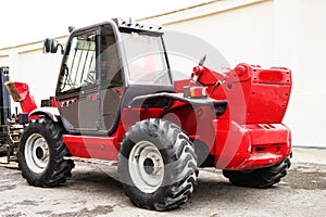 A red forklift truck stands on a rough terrain in the yard